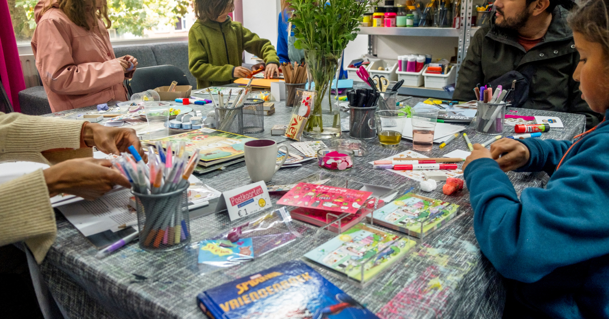 Kinderen en volwassenen knutselen samen aan een volle tafel in een creatieve workshopruimte. Kinderen en volwassenen knutselen samen aan een volle tafel in een creatieve workshopruimte.