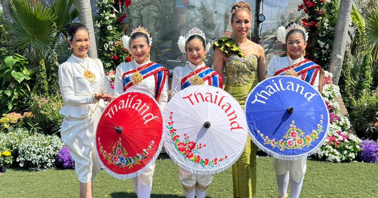 Poserende dames in traditionele Thaise kleding met papieren parasolletjes naar voren gericht Poserende dames in traditionele Thaise kleding met papieren parasolletjes naar voren gericht