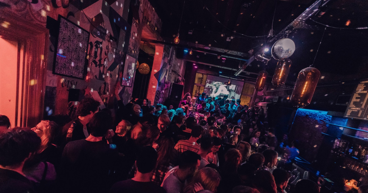 Drukke dansvloer in het Paardcafé in Den Haag, met feestende mensen, kleurrijke verlichting en een levendige sfeer.