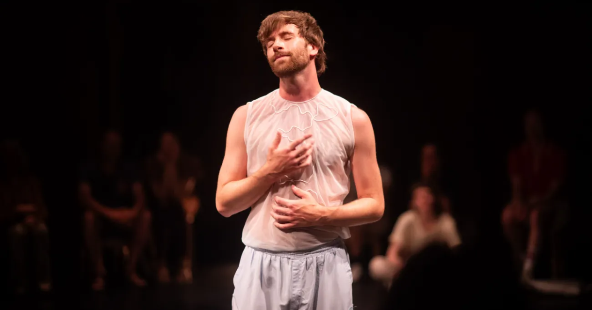Philip Cahrpit staat op het podium in zijn theatervoorstelling Wanderlust. Hij draagt lichte losse kleding en heeft zijn ogen dicht. Philip Cahrpit staat op het podium in zijn theatervoorstelling Wanderlust. Hij draagt lichte losse kleding en heeft zijn ogen dicht.