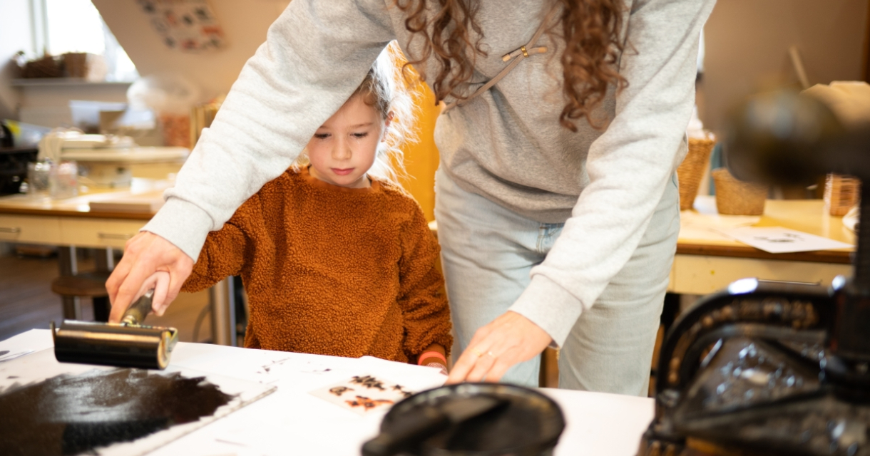 Kind drukt met hulp af tijdens creatieve workshop Kind drukt met hulp af tijdens creatieve workshop