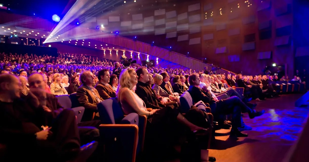Publiek geniet van show in volle theaterzaal Publiek geniet van show in volle theaterzaal