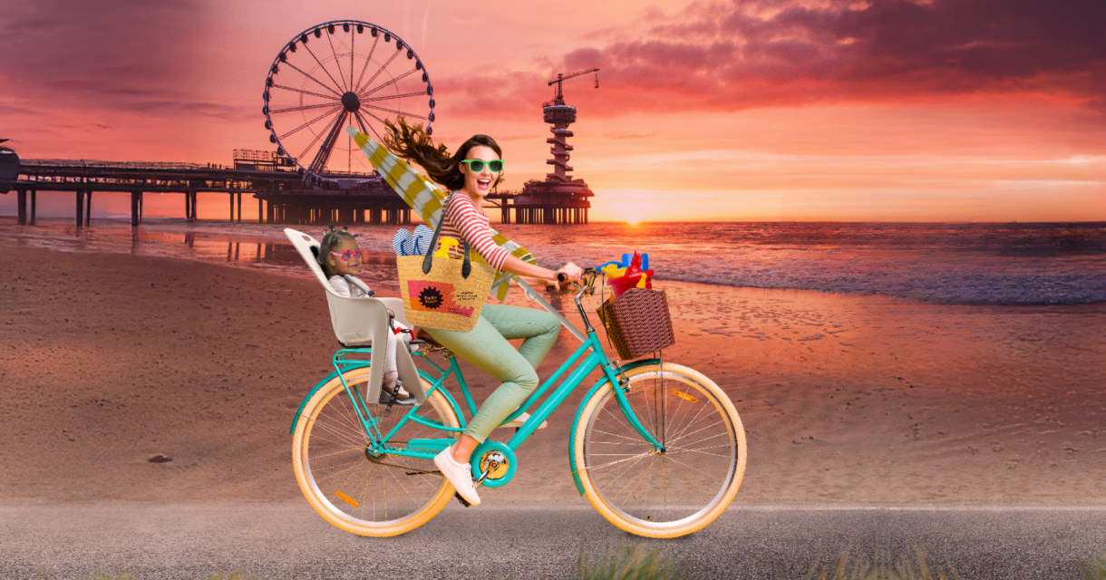 Fictief beeld van een vrouw op een fiets op het strand in Scheveningen en een kindje achterop