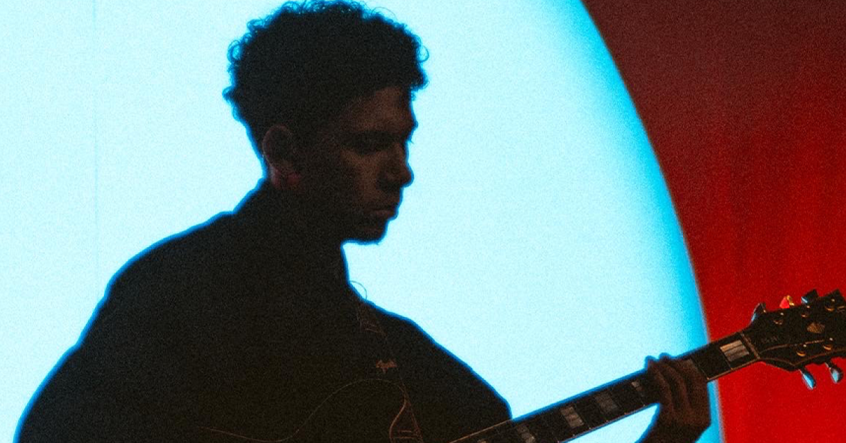 Portret van gitarist en producer Rafael Devánte Sinay in schaduw met een gitaar wat bpast bij de eerbetoon van de Nationale herdenking op 15 augustus. Portret van gitarist en producer Rafael Devánte Sinay in schaduw met een gitaar wat bpast bij de eerbetoon van de Nationale herdenking op 15 augustus.