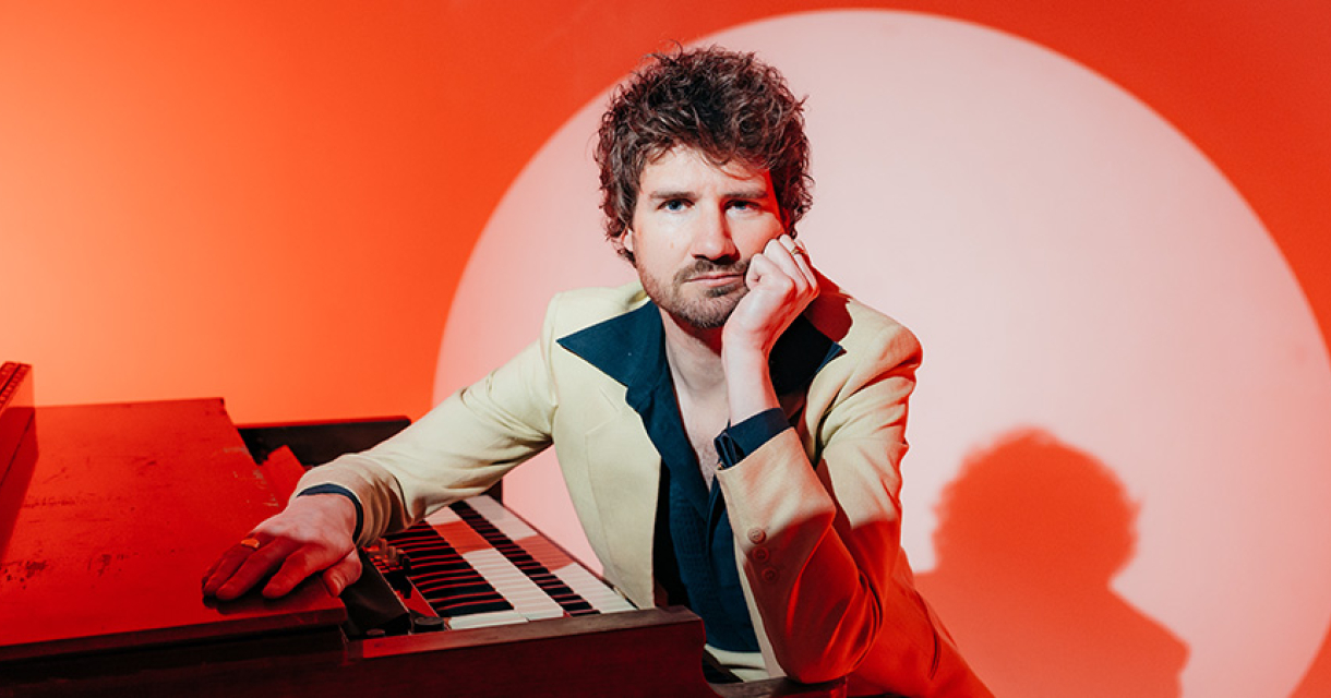 Thijs Boontjes in zwart overhemd met puntkraag en licht pak voor een sixties setting met oranje achtergrond en wit spotlight circel wat de sfeer ademt van rock‑’n‑roll, italo en Nederpop tot één dansfeest. Thijs Boontjes in zwart overhemd met puntkraag en licht pak voor een sixties setting met oranje achtergrond en wit spotlight circel wat de sfeer ademt van rock‑’n‑roll, italo en Nederpop tot één dansfeest.
