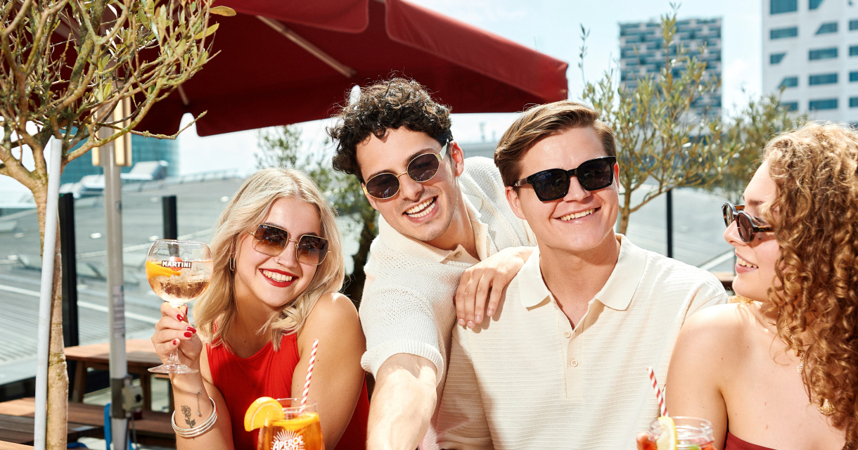 Vier vrienden genieten van pizza en cocktails op een zonnig stads terras. Vier vrienden genieten van pizza en cocktails op een zonnig stads terras.