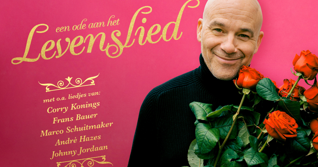 Chris Grem draagt zwarte coltrui. Hij heeft een bos rozen vast en kijkt lachend in de camera. Chris Grem draagt zwarte coltrui. Hij heeft een bos rozen vast en kijkt lachend in de camera.