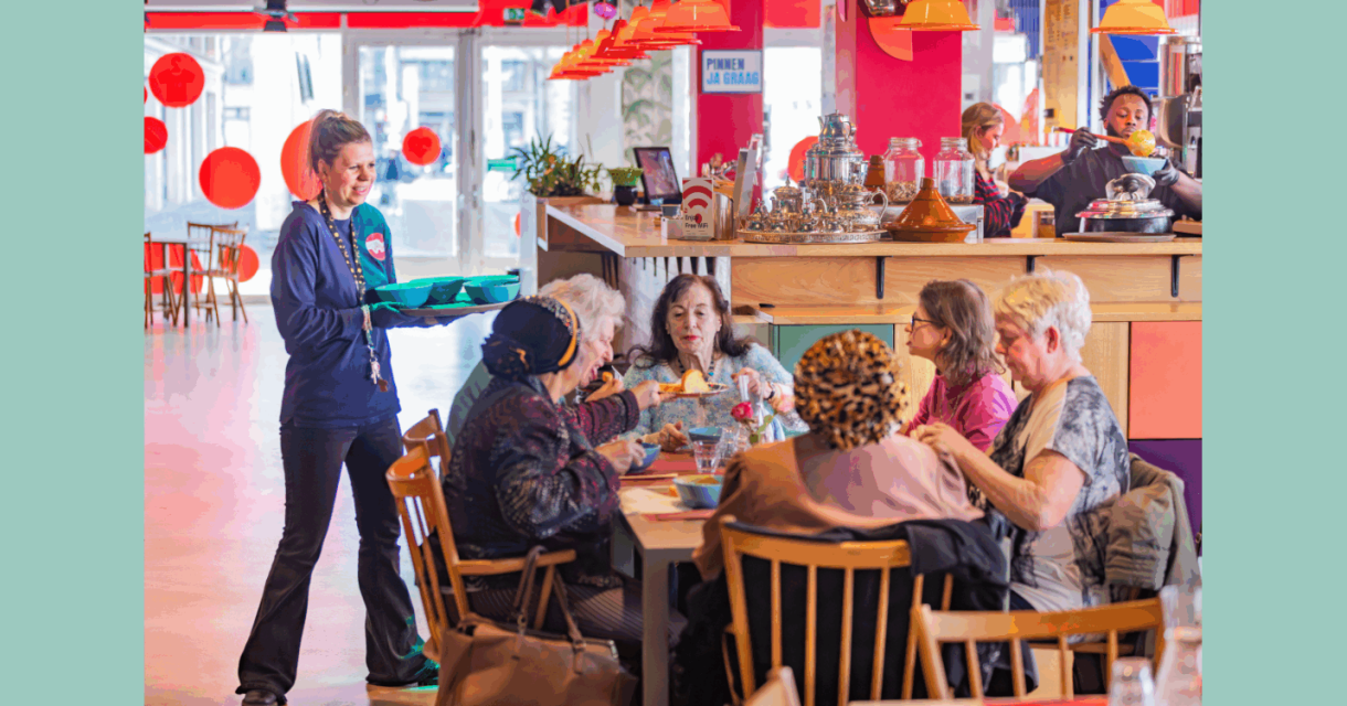 Buurtbewoners lunchen samen aan een lange tafel