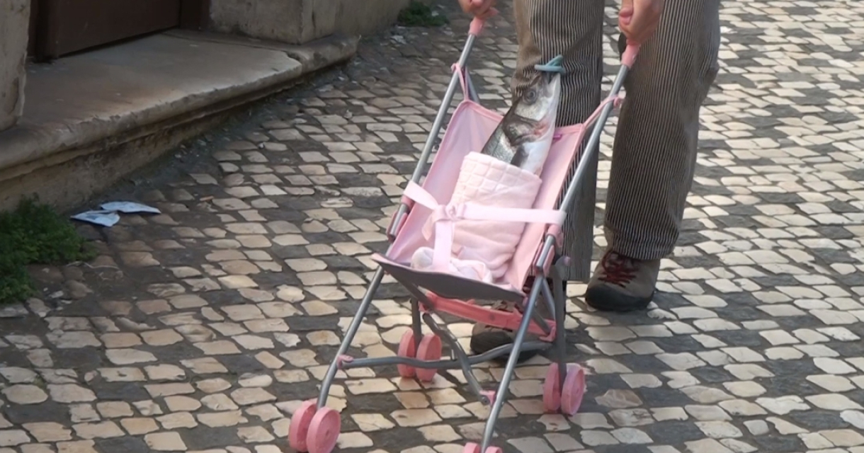 Vis in roze kinderwagen op straatstenen trottoir Vis in roze kinderwagen op straatstenen trottoir