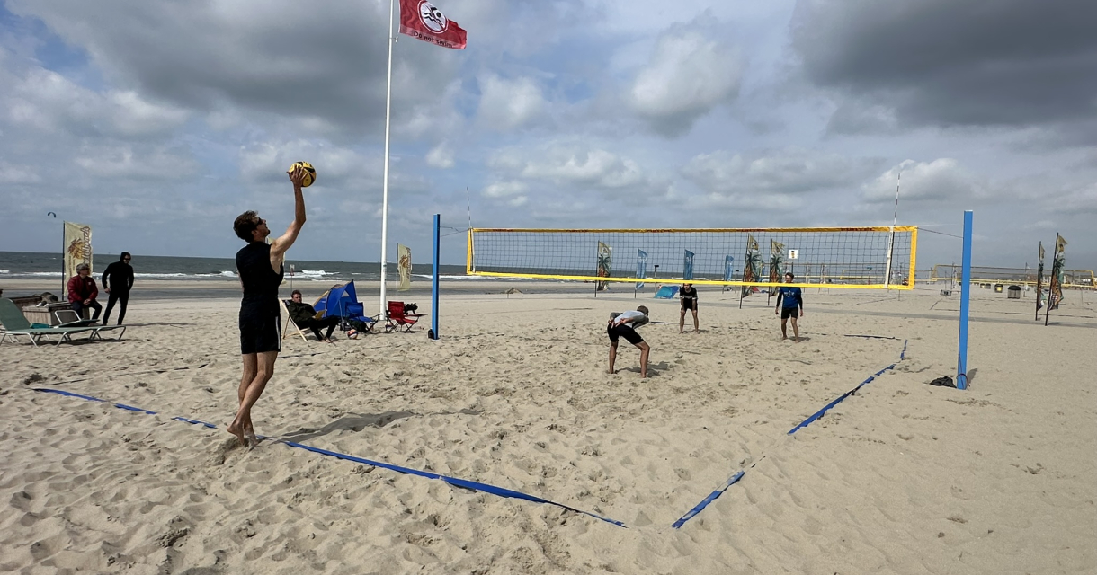 Beachsportfestival Kijkduin op het strand met man die volleybal raakt ter sfeerimpressie.