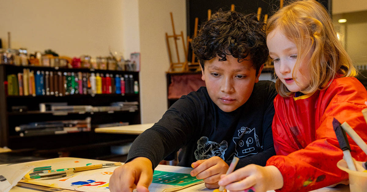 Two children painting together at a workshop Two children painting together at a workshop