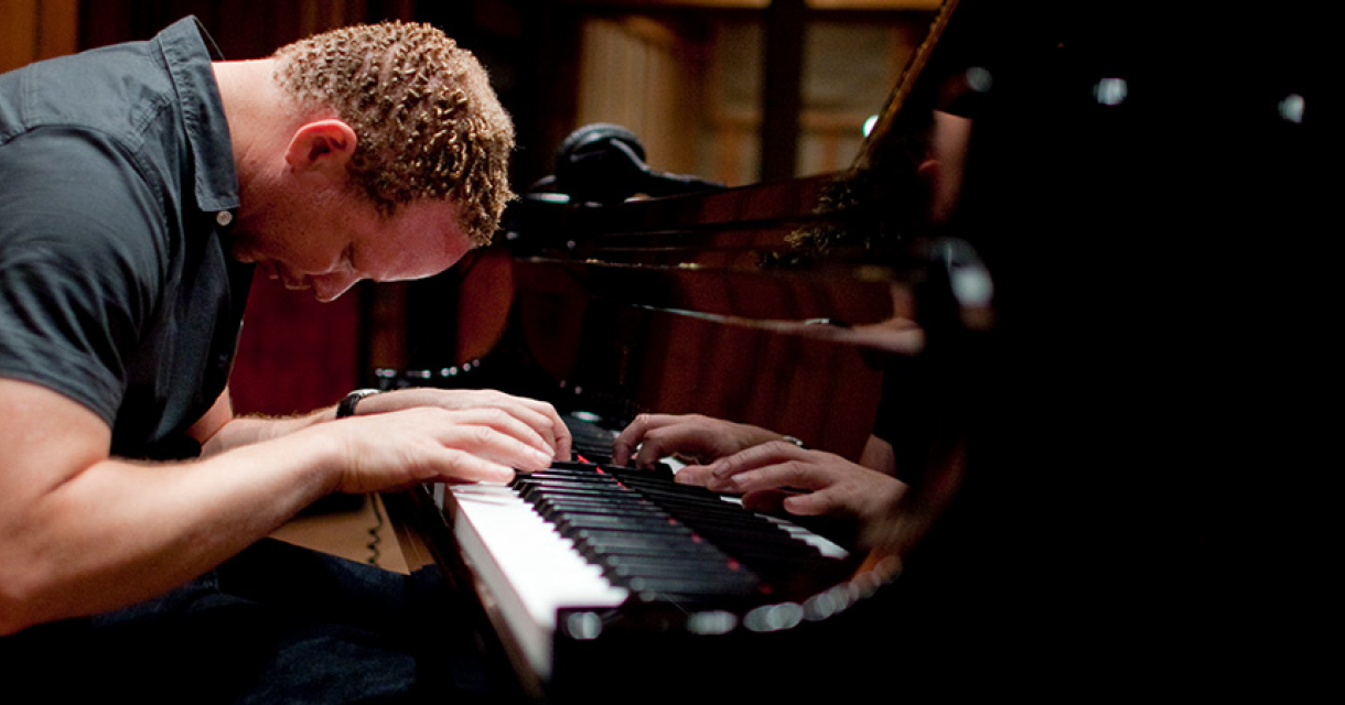 Pianist Craig Taborn voorover gebogen over zijn piano wat emotie en inleving toont.