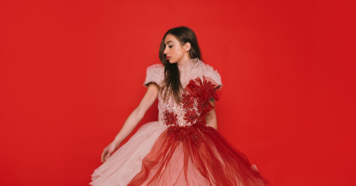 Soul en popzangeres Nona in rode galajurk voor rode achtergrond.