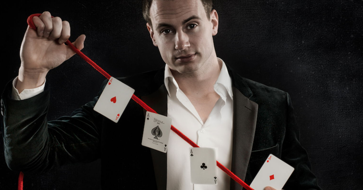 Een goochelaar in een chic pak voert een kaartentruc uit. 