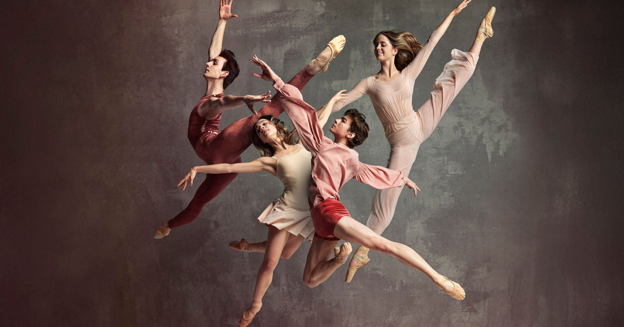 Vier balletdansers in sprongpose tegen een neutrale achtergrond 