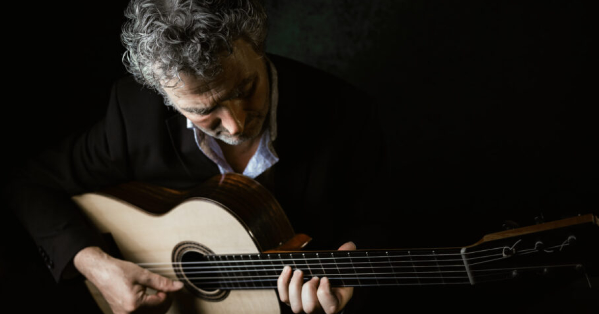 Een man speelt gitaar, met een geconcentreerde blik.