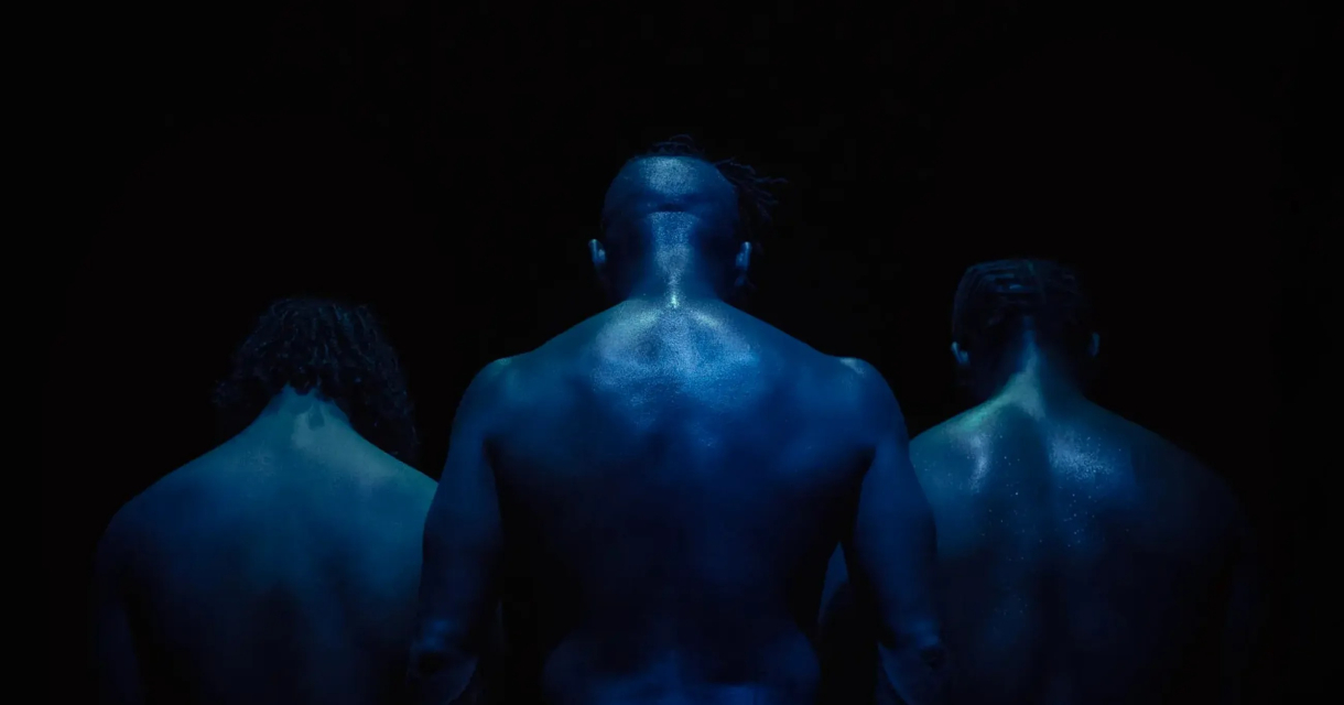 Drie blote mensen van achteren, gehuld in blauw licht.