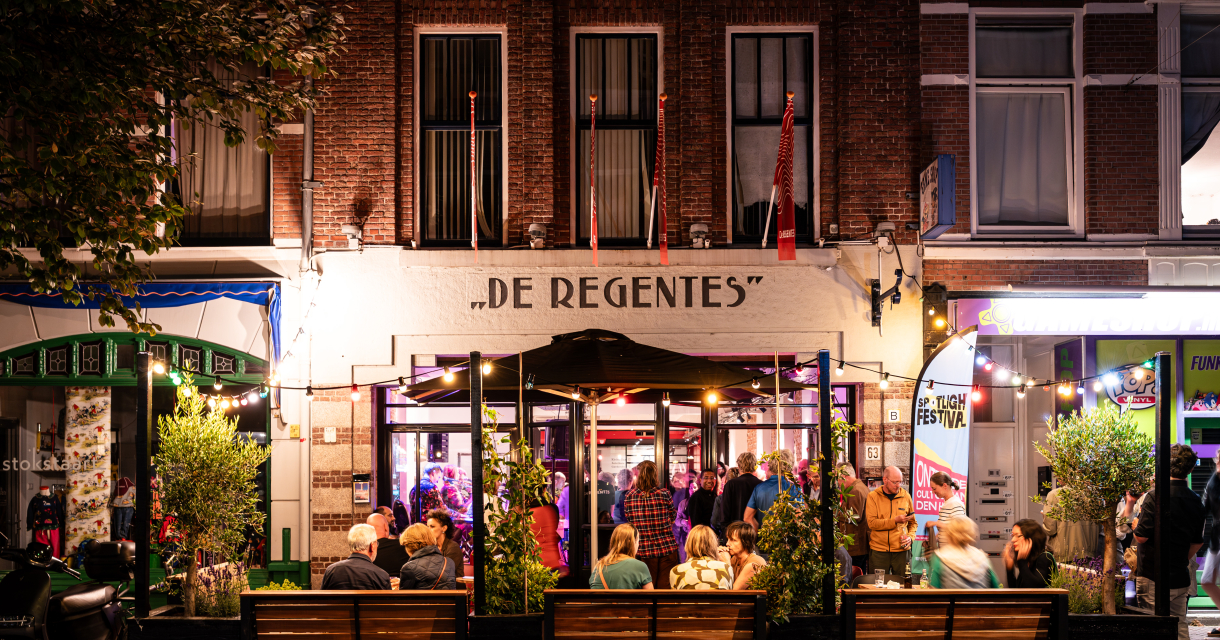 Busy street with people sitting outside the café De Regentes.