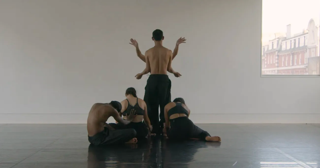 Een groep dansers in een studio, met een danser in het midden.