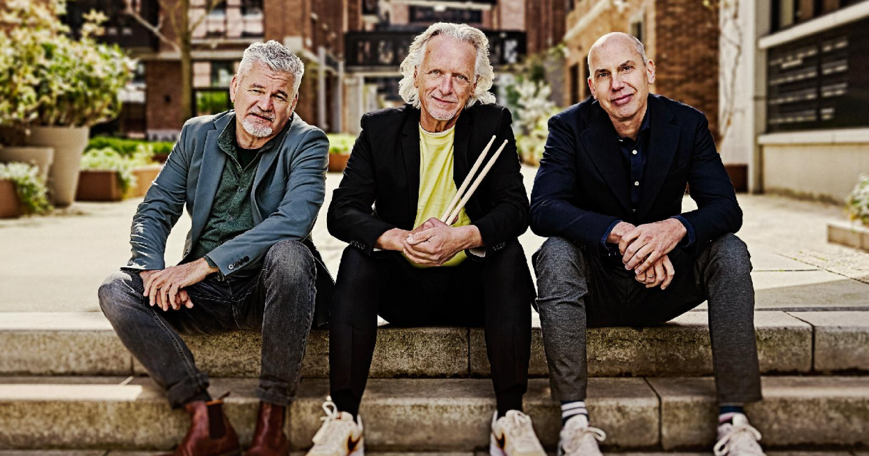 Drie mannen zitten op een trap in een stedelijke omgeving.