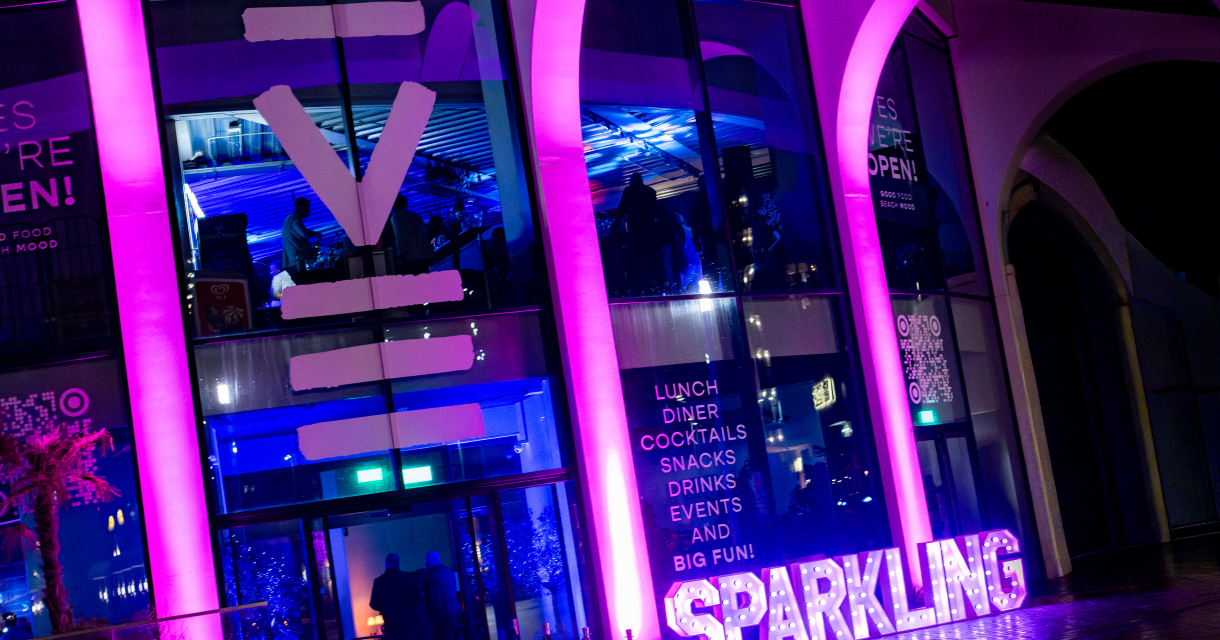 Een café met de naam 'SPARKLING' in neonverlichting.