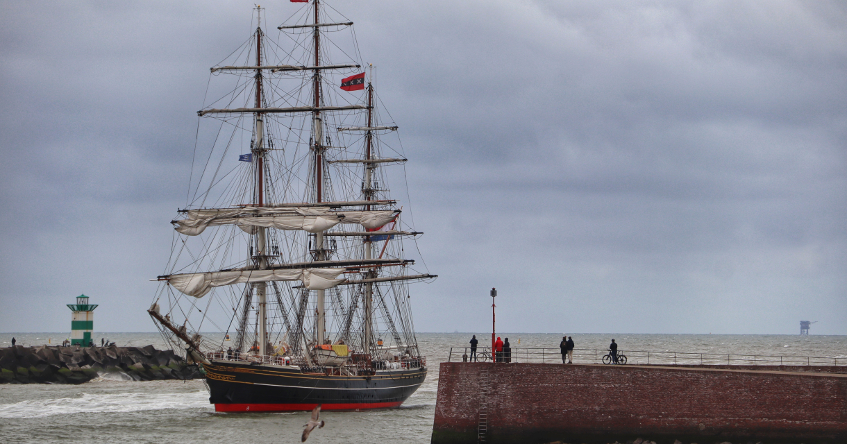 Een groot zeilschip vaart de haven van Scheveningen binnen.