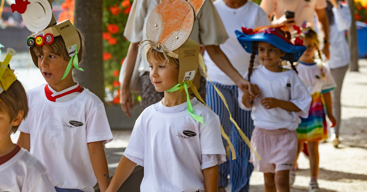 Groep kinderen gehouden handen en dragen kleurige hoedjes tijdens een festiviteit. ©From Our Dot fotografie