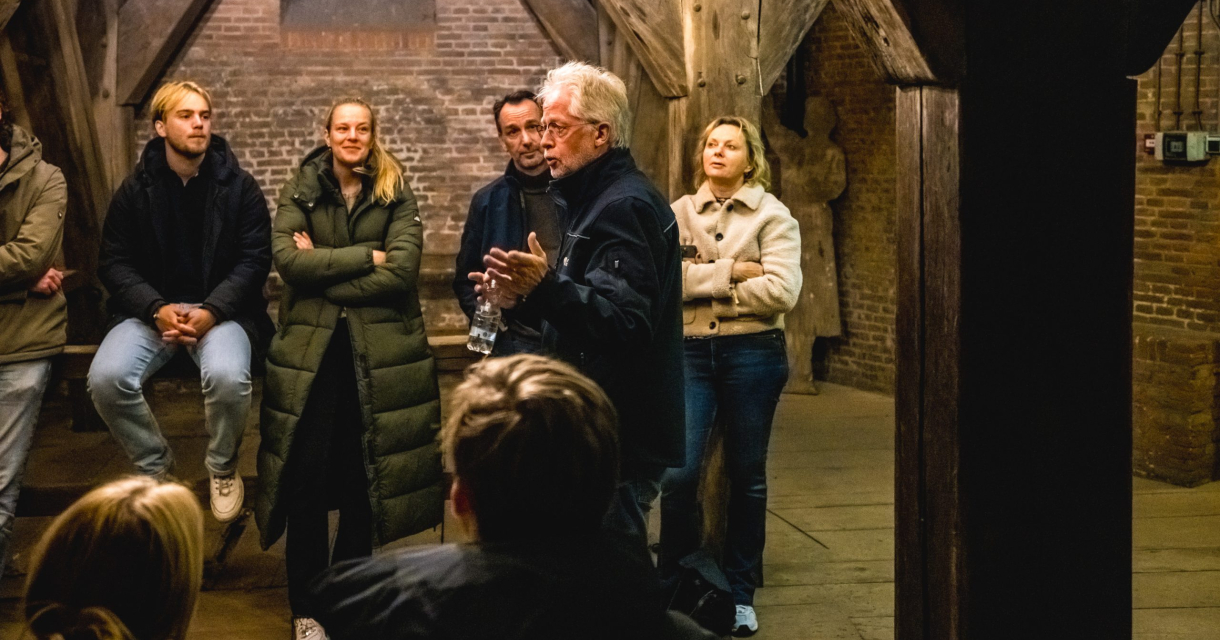Groep mensen luistert naar de gids tijdens een beklimming van de Haagse Toren