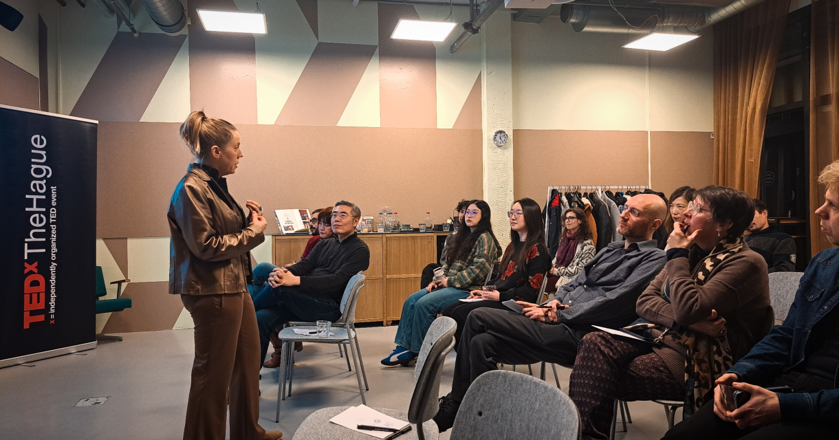 Een vrouw aan het woord voor een zaal met mensen tijdens een TEDx