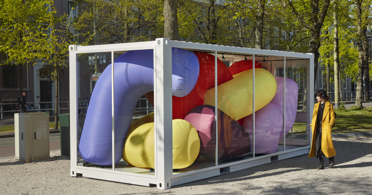 Mens in een gele jas kijkt naar een kleurrijke kunstinstallatie