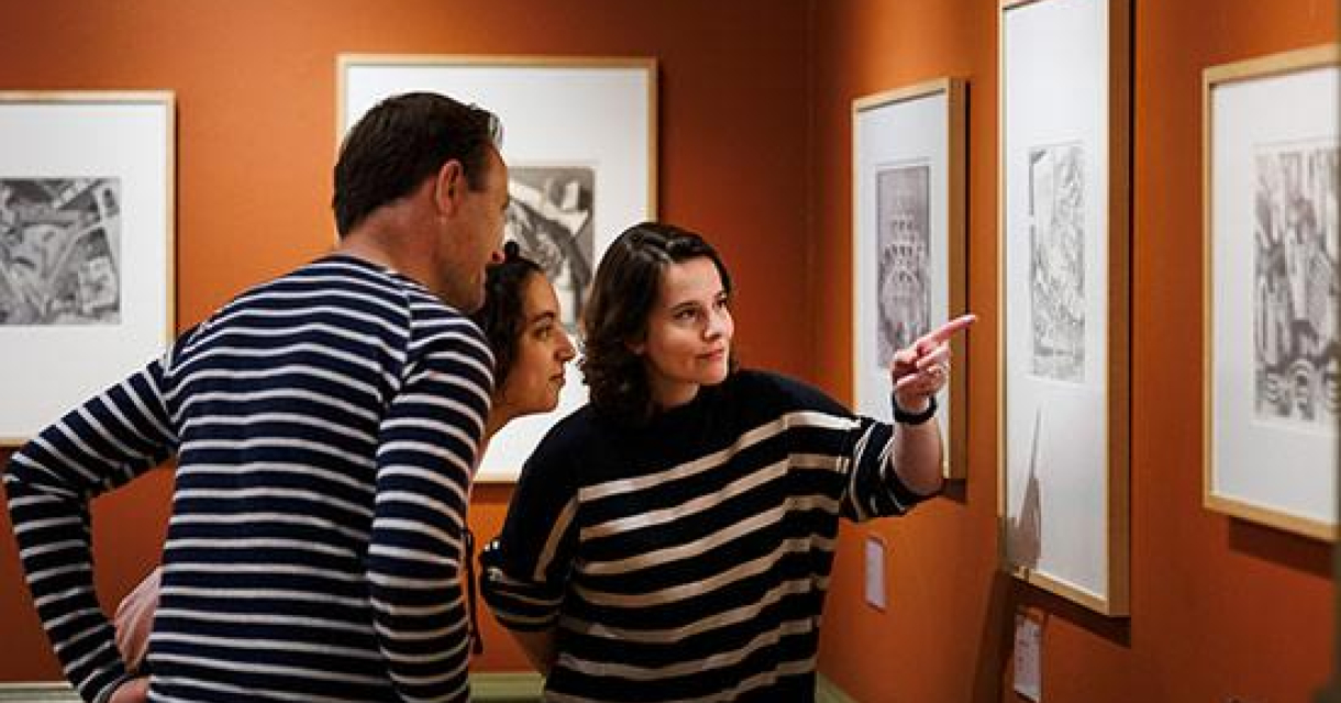 Drie mensen bekijken kunstwerken in een galerie.