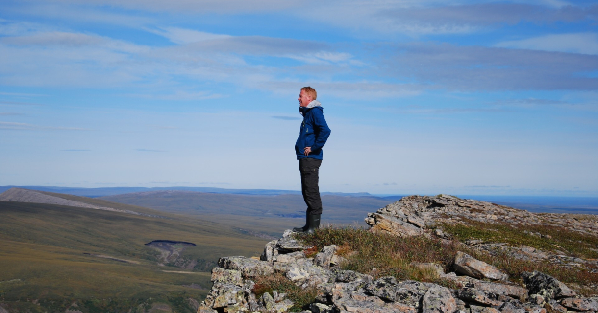Een man staat op een rotsachtige bergtop met uitzicht op een vallei.