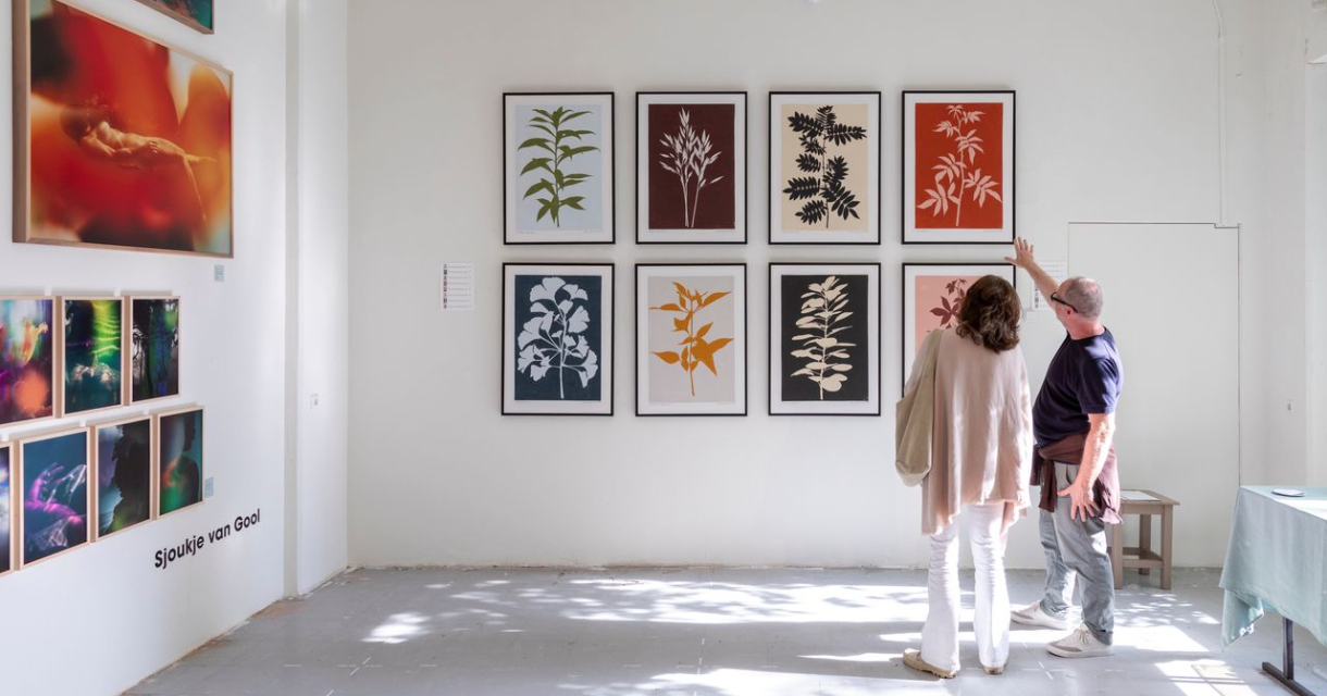 Twee mensen bekijken kunstwerken in een galerie.