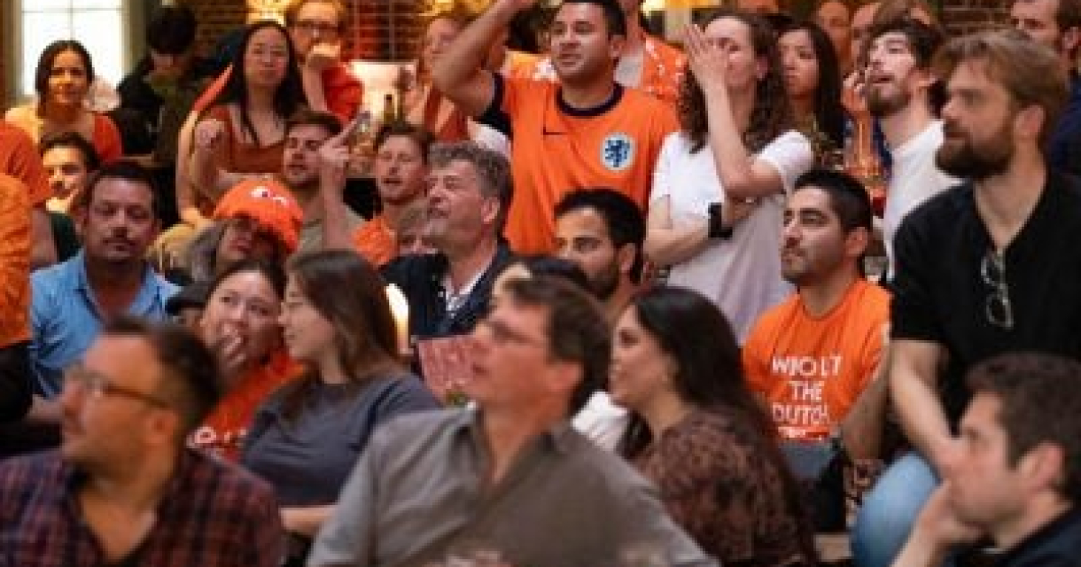 Een menigte kijkt gespannen naar een sportwedstrijd, gekleed in oranje.