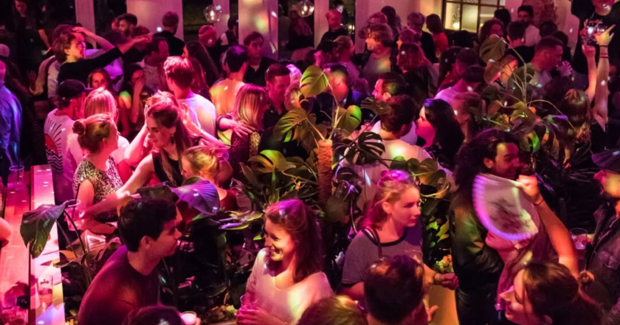 A crowded party venue with people dancing and socializing.