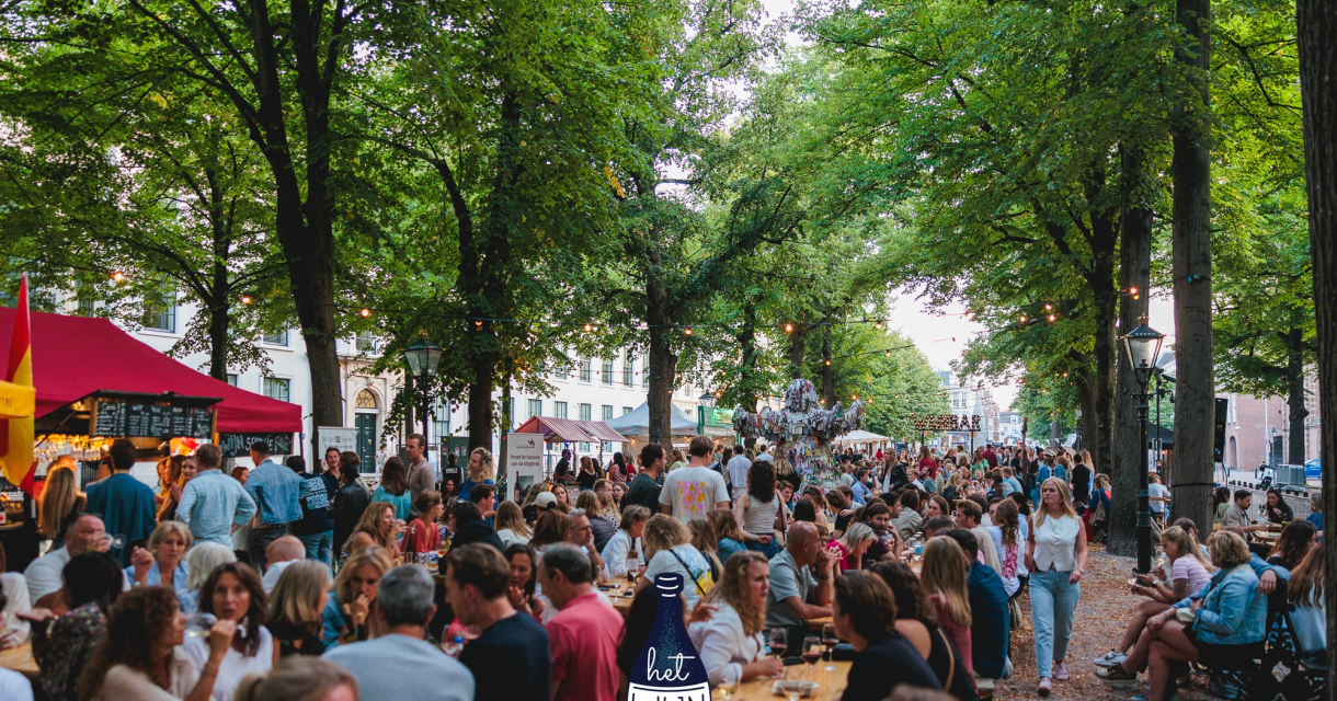 Drukke wijnfestival met tafels, mensen en kraampjes onder bomen