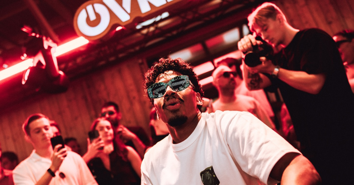 Dj Menesix draait muziek in een clubomgeving met publiek.