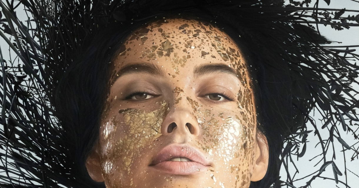 Een portret van een persoon met gouden schmink op het gezicht.