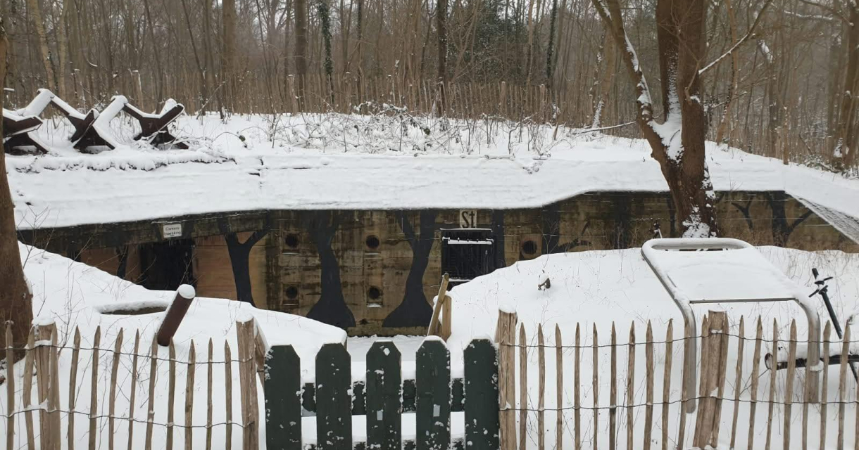 Sneeuwbedekt bunker met een houten hek en bomen