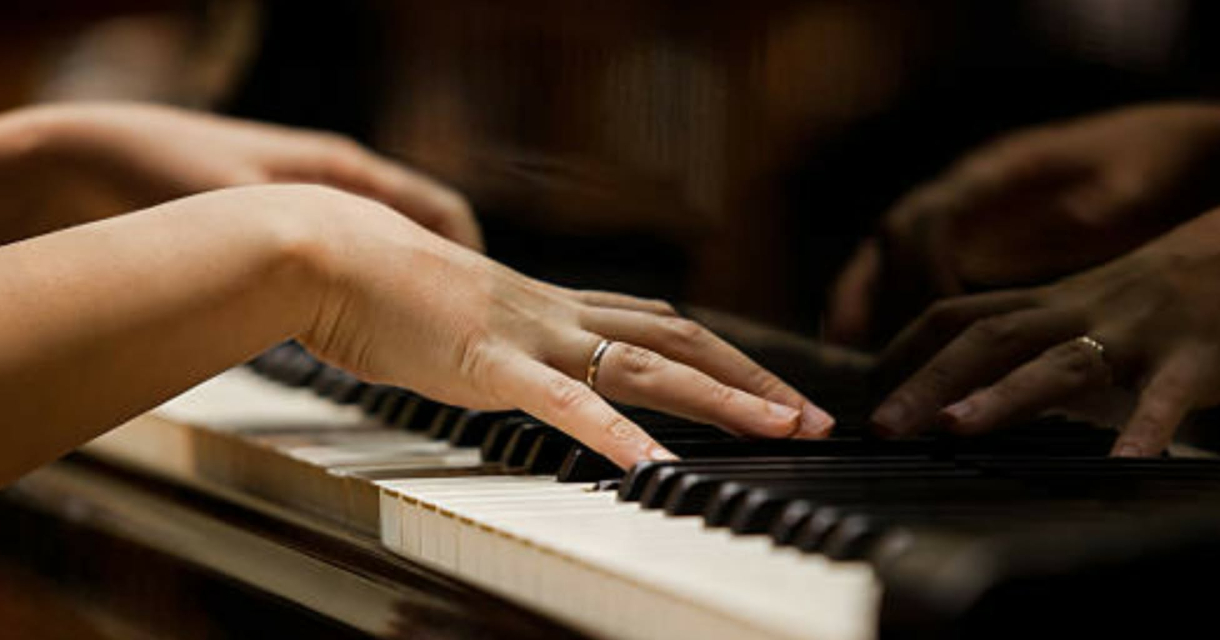 Twee handen bespelen de toetsen van een piano