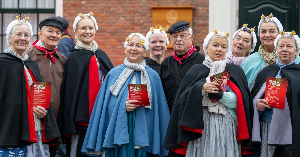 Five women and one man in traditional attire, smiling and posing.