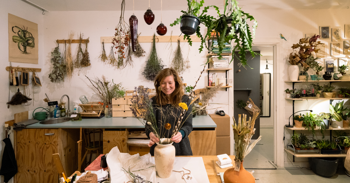 Verkoopster die een bloemenboeket samenstelt in een planten- en vintagewinkel
