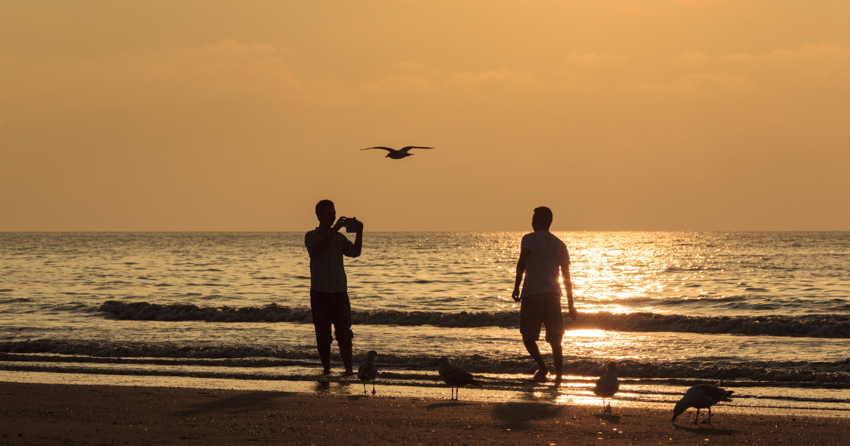 Twee mensen bij zonsondergang op het strand.