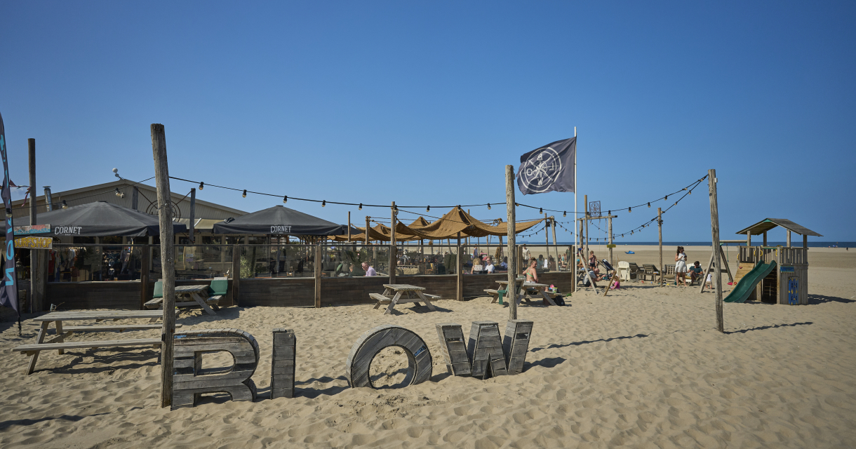Une plage bar nommée Blow avec des parasols et des gens sur la plage.