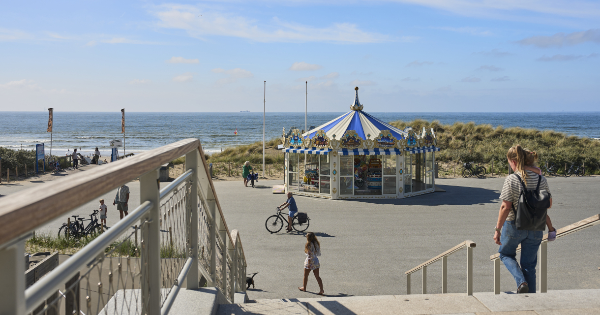 Un carrousel près de la plage avec des cyclistes et des piétons autour.