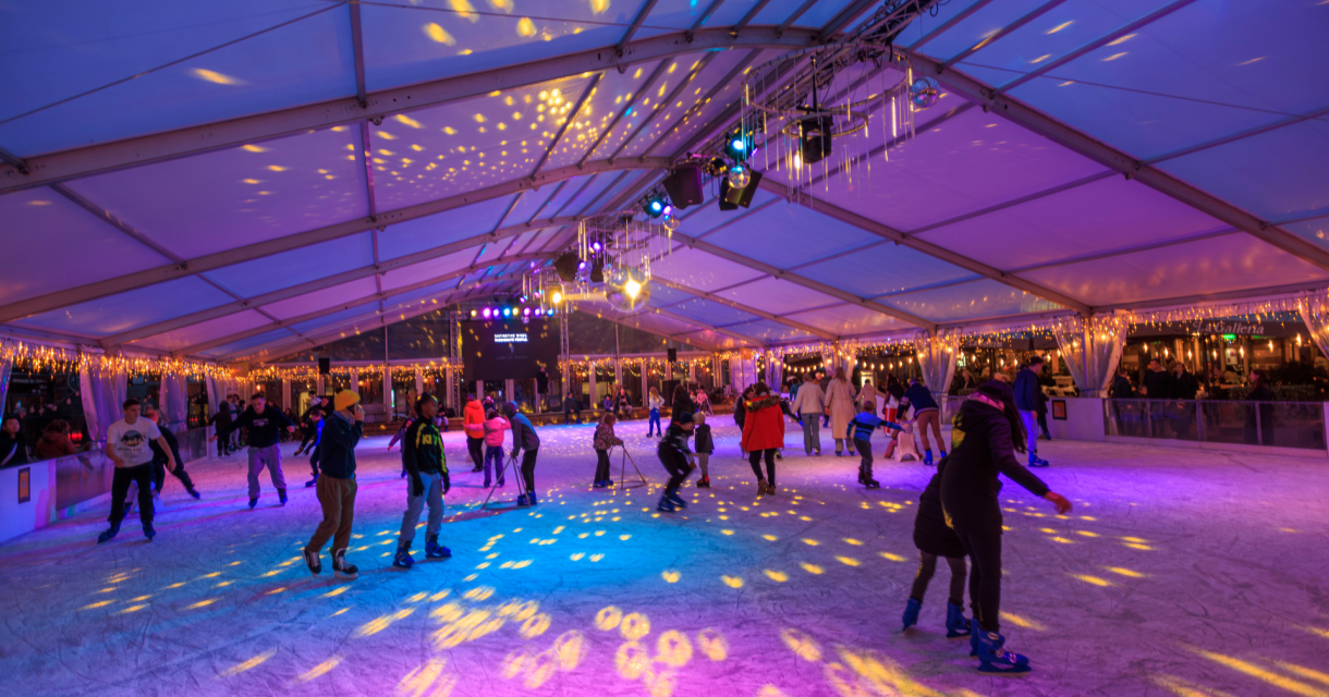 People skating on an ice rink with colorful lights.