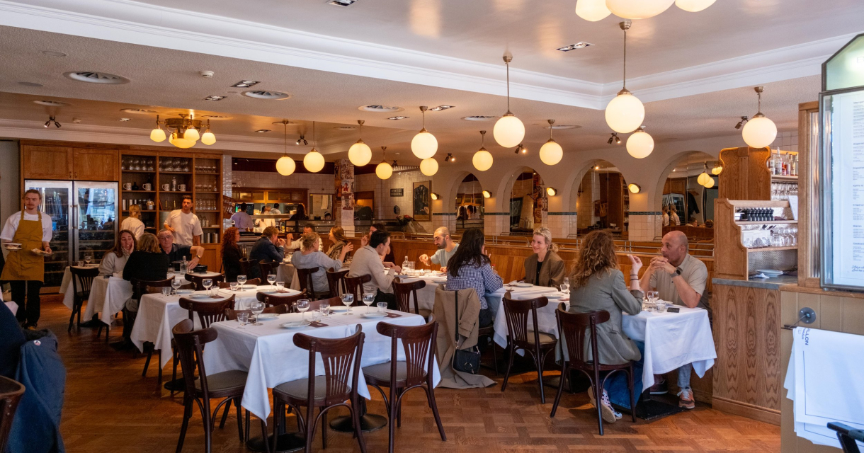 Een druk restaurant met gasten en een serveerder.