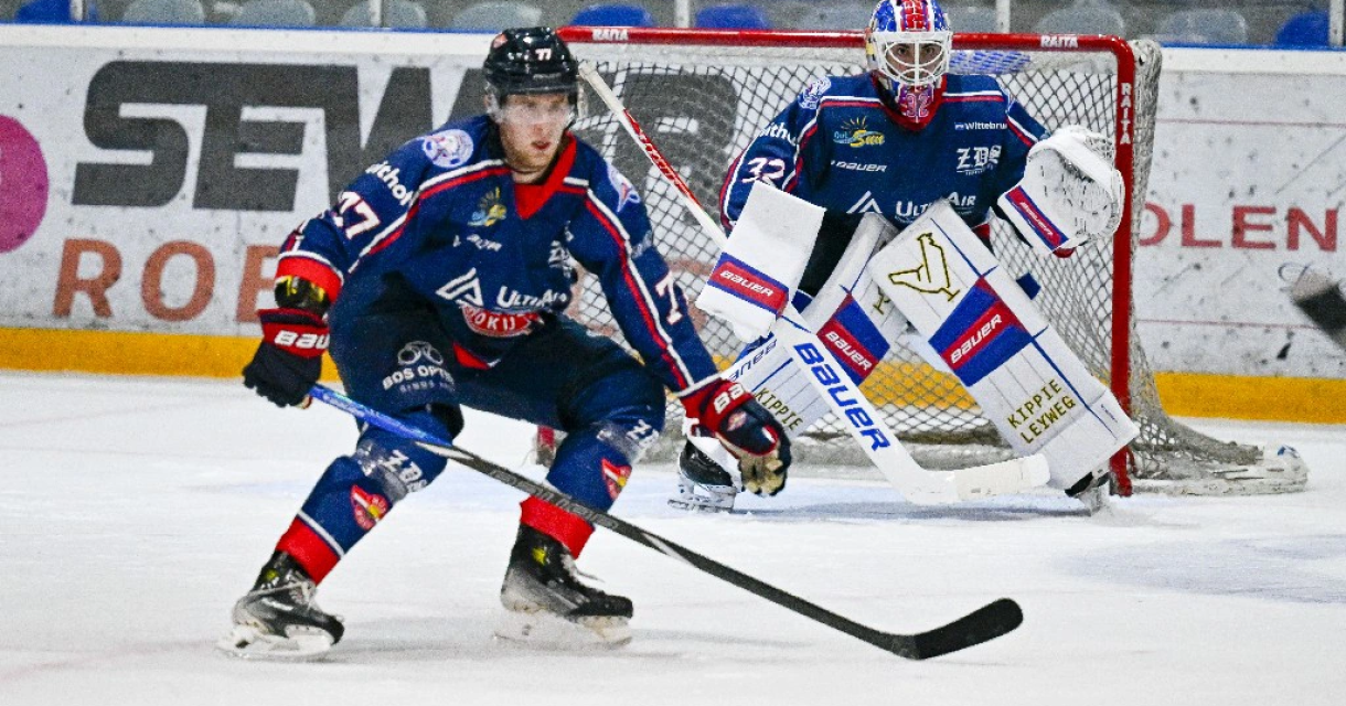 Een ijshockeyspeler van HIJS met puck en keeper op achtergrond
