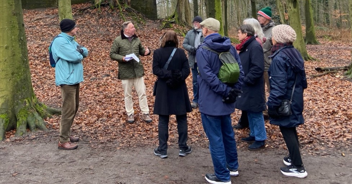 Een gids vertelt aan een groep mensen in het bos.