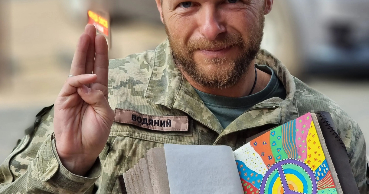 Een soldaat toont een tekenboek met een vredessymbool.